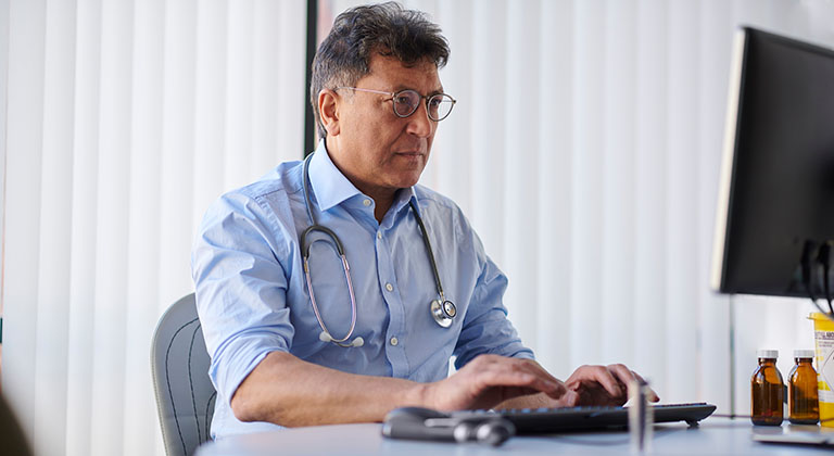 Male doctor working at his desktop computer