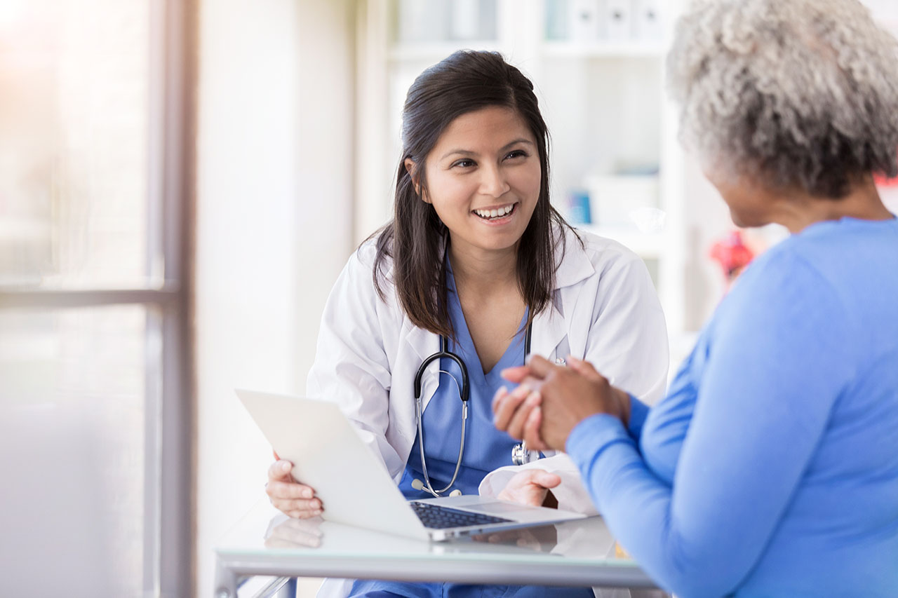 Smiling female doctor talking to a female patient in front of a laptop